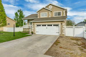 View of front of home featuring a gate, stucco siding, a front lawn, and a garage