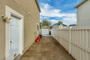 View of side of home featuring a residential view, driveway, fence, a garage, and stucco siding