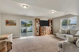 Carpeted living room with a wealth of natural light, visible vents, and baseboards
