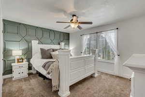 Bedroom featuring a ceiling fan, baseboards, and light carpet