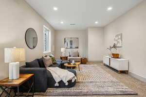 Living room with baseboards, recessed lighting, visible vents, and light colored carpet