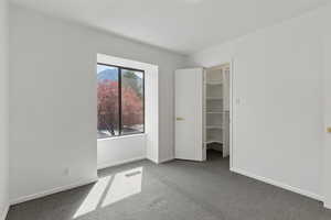 Unfurnished bedroom with carpet flooring, visible vents, a closet, baseboards, and a spacious closet