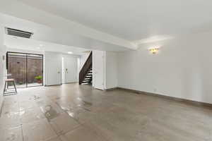 Unfurnished living room with stairway, visible vents, and baseboards