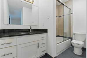 Full bath featuring tile patterned floors, toilet, enclosed tub / shower combo, and vanity