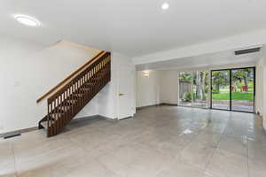 Unfurnished living room with stairs, visible vents, and baseboards