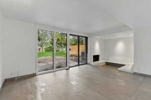 Tiled spare room with baseboards and a fireplace