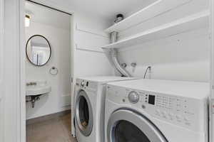 Clothes washing area featuring light tile patterned flooring, washer and dryer, and baseboards