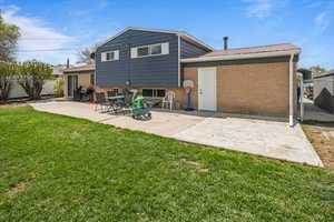 Rear view of property featuring fence, a yard, brick siding, and metal roof