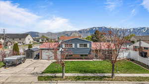 View of front of home with a residential view, concrete driveway, fence, and a mountain view