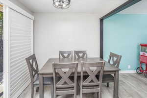 Dining space with wood finished floors, a notable chandelier, and baseboards