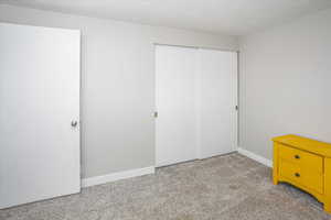 Unfurnished bedroom with a closet, light colored carpet, and baseboards