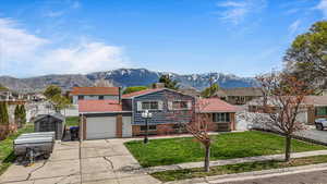 Split level home featuring metal roof, a mountain view, driveway, an attached garage, and fence