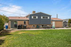 Back of house with metal roof, a patio, and brick siding