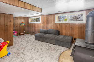 Carpeted living area with wood walls, a textured ceiling, and visible vents