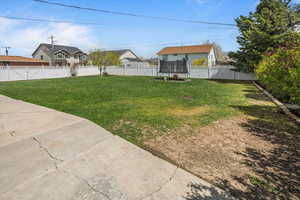 View of yard featuring a trampoline and a fenced backyard
