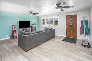 Living room featuring ceiling fan, light wood-style flooring, and baseboards