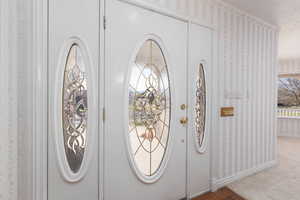 Foyer entrance with wallpapered walls and baseboards