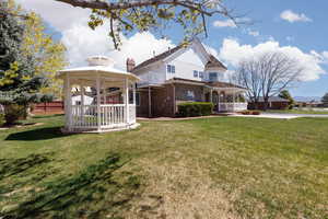 Exterior space featuring a gazebo, a front lawn, covered porch, fence, and brick siding