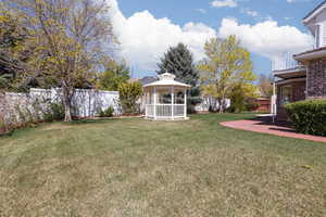 View of yard with a fenced backyard, a gazebo, and a balcony