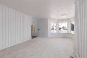 Interior space with wallpapered walls, arched walkways, and a textured ceiling