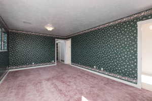 Carpeted spare room with baseboards, a textured ceiling, and wallpapered walls
