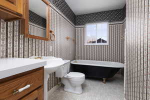 Bathroom featuring toilet, a soaking tub, a textured ceiling, and wallpapered walls