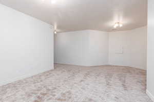 Carpeted spare room featuring a textured ceiling and baseboards