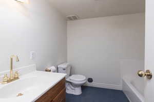 Bathroom featuring visible vents, toilet, vanity, a bathing tub, and a textured ceiling