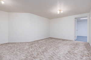 Carpeted empty room featuring baseboards and a textured ceiling