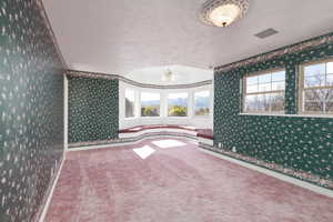 Carpeted spare room with wallpapered walls, baseboards, visible vents, and a textured ceiling