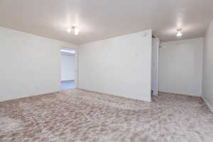 Spare room featuring baseboards, a textured ceiling, and carpet