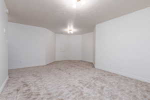 Carpeted spare room featuring baseboards and a textured ceiling