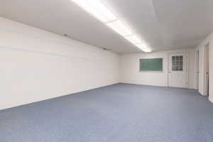 Spare room featuring baseboards, dark carpet, and a textured ceiling