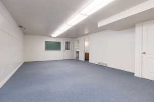 Unfurnished room featuring dark carpet, baseboards, and visible vents