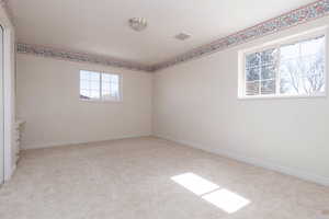 Carpeted spare room with visible vents and baseboards