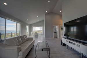 Living room with recessed lighting, high vaulted ceiling, wood finished floors, and baseboards