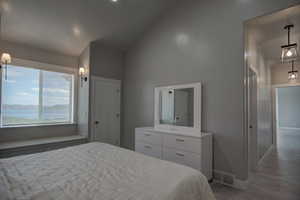 Bedroom featuring visible vents, vaulted ceiling, wood finished floors, and baseboards