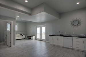 Kitchen featuring a sink, dark countertops, open floor plan, dishwasher, and light wood finished floors