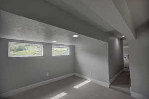 Below grade area with recessed lighting, a textured ceiling, carpet flooring, and baseboards