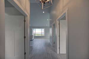 Hallway with a notable chandelier, wood finished floors, and baseboards