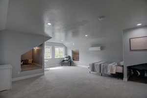 Carpeted bedroom featuring lofted ceiling, a wall mounted air conditioner, recessed lighting, and baseboards