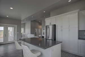Kitchen with white cabinets, dark countertops, freestanding refrigerator, recessed lighting, and french doors