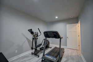Exercise room featuring baseboards, light wood-type flooring, and recessed lighting