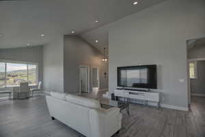 Living room featuring wood finished floors, recessed lighting, high vaulted ceiling, and baseboards