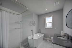 Bathroom featuring visible vents, a soaking tub, vanity, and tiled shower