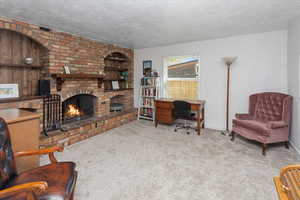 Carpeted living room featuring a brick fireplace, a textured ceiling, and baseboards
