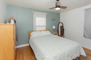 Bedroom featuring wood finished floors, a ceiling fan, and baseboards