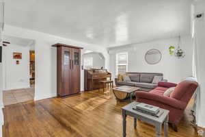 Living area with wood finished floors, baseboards, and arched walkways
