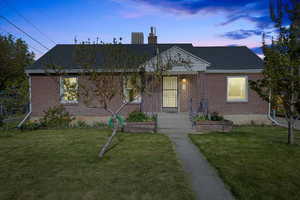 Bungalow-style house featuring a lawn, a chimney, and brick siding