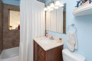 Full bathroom featuring shower / tub combo, a notable chandelier, toilet, and vanity